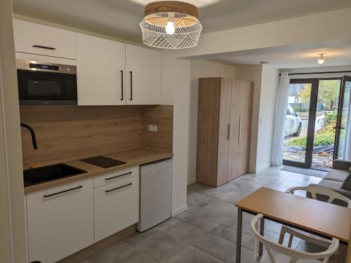 a kitchen with white cabinets and a table and a dining room at Studio indépendant en rez-de-jardin in Cesson-Sévigné