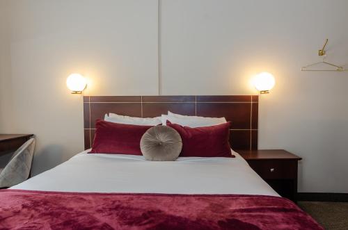 a bedroom with a large bed with red pillows at Hotel Dorion in Montréal