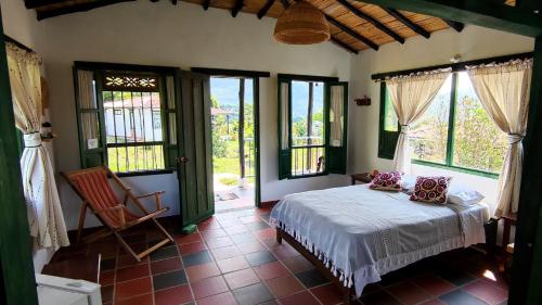 a bedroom with a bed in a room with windows at Santa Lucia Estancia Rural in Guaduas