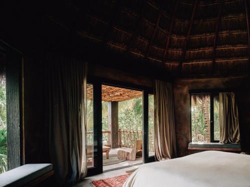 a bedroom with a bed and large windows at Nomade Tulum in Tulum
