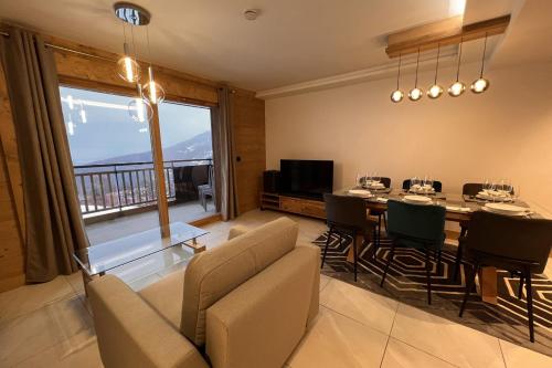 uma sala de estar com uma mesa e cadeiras e uma televisão em Pretty cocoon overlooking the slopes em La Plagne Tarentaise