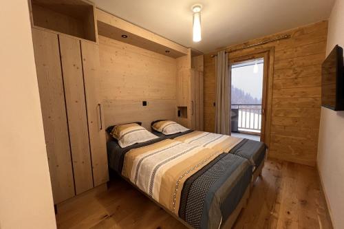 um quarto com uma cama e uma grande janela em Pretty cocoon overlooking the slopes em La Plagne Tarentaise