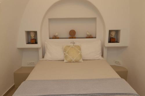 a bedroom with a white bed with a pillow on it at Santorini Cave Suite in Éxo Goniá