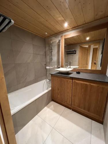 uma casa de banho com uma banheira e um lavatório e uma banheira em Pretty cocoon overlooking the slopes em La Plagne Tarentaise