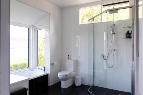 a white bathroom with a toilet and a shower at Woodland Bay Retreat-Luxury Hamptons Retreat in Lymington