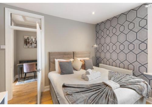 a bedroom with a large bed with a gray wall at Chic & Radiant Retreat in Harringay Ladder in London