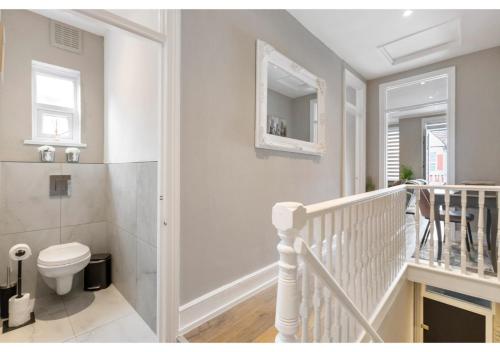 a white bathroom with a toilet and a staircase at Chic & Radiant Retreat in Harringay Ladder in London