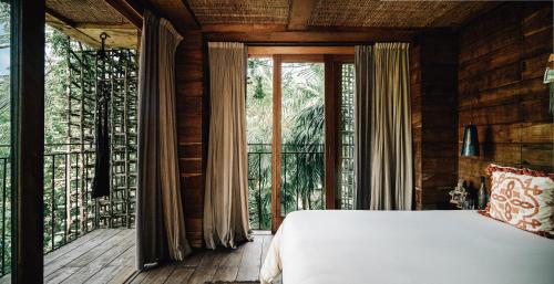 a bedroom with a bed and a large window at Nômade Temple Tulum in Tulum
