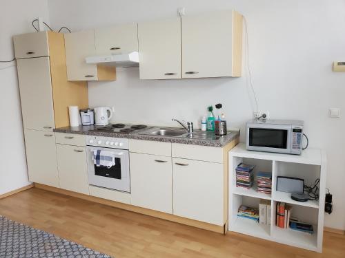 een keuken met witte kasten, een wastafel en een magnetron bij Schubert Park Apartment near Volksopera Vienna in Wenen