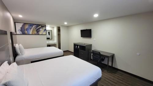 a hotel room with two beds and a desk at Travelodge by Wyndham Buena Park in Buena Park