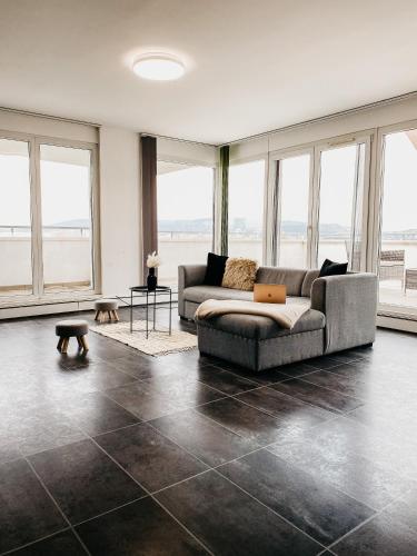 a living room with a couch and large windows at Highrise Horizon Penthouse in Budapest