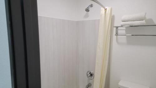 a bathroom with a shower with a toilet and towels at Travelodge by Wyndham Buena Park in Buena Park