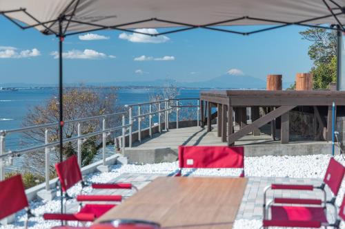 a deck with a wooden table and red chairs at 【南房テラス】180度パノラマオーシャンビュー絶景を楽しむリゾート別荘の家 in Kanaya