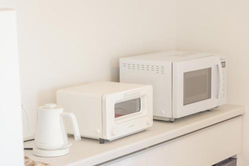 a microwave and a toaster oven on a shelf at 【南房テラス】180度パノラマオーシャンビュー絶景を楽しむリゾート別荘の家 in Kanaya