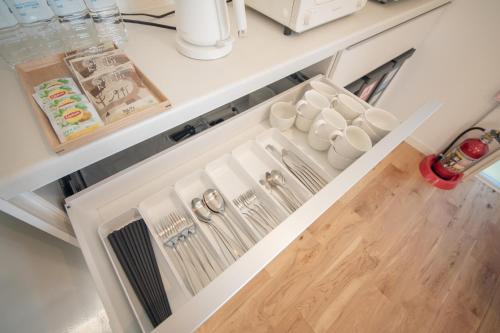 an open kitchen drawer with cups and dishes at 【南房テラス】180度パノラマオーシャンビュー絶景を楽しむリゾート別荘の家 in Kanaya