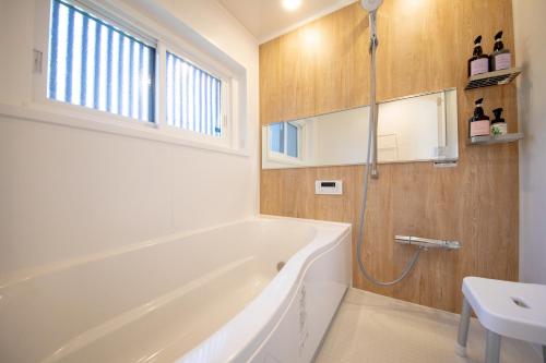 a bathroom with a white tub and a sink at 【南房テラス】180度パノラマオーシャンビュー絶景を楽しむリゾート別荘の家 in Kanaya