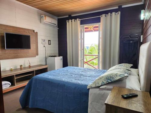 a bedroom with a blue bed and a television at Beto Pousada in Penha