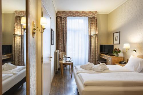 a hotel room with two beds and a window at Grand Hotel Beau Rivage Interlaken in Interlaken