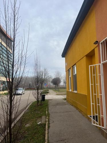 a yellow building with a sidewalk next to a street at OLD TISA Apartment in Senta