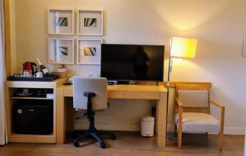 uma secretária com um computador, um monitor e uma cadeira em Linda suite em hotel ao lado do aeroporto de Congonhas em São Paulo