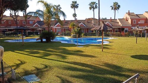 un complejo con una gran piscina con palmeras en Nueces y Horkillas Novo Sancti Petri en Chiclana de la Frontera