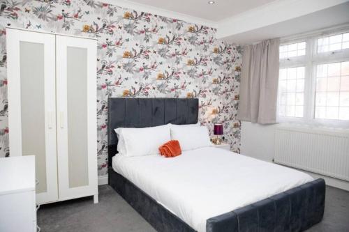 a bedroom with a white bed with floral wallpaper at A hidden Gem in the heart of Dagenham! in Goodmayes