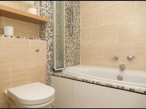 a bathroom with a toilet and a bath tub and a sink at A hidden Gem in the heart of Dagenham! in Goodmayes