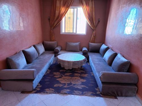 een woonkamer met een bank en een tafel bij Grand T3 meublé et propre in Agadir