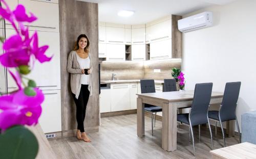 a woman standing in a kitchen next to a table at Trika Apartman in Sárvár