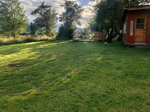 a large yard with a house in the background at Cabaña Kataleya Rio Puelo in Cochamó