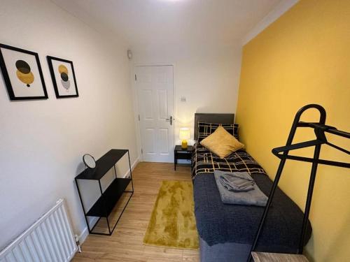 a small bedroom with a bed and a yellow wall at Elegant room in stylish house in Milton Keynes