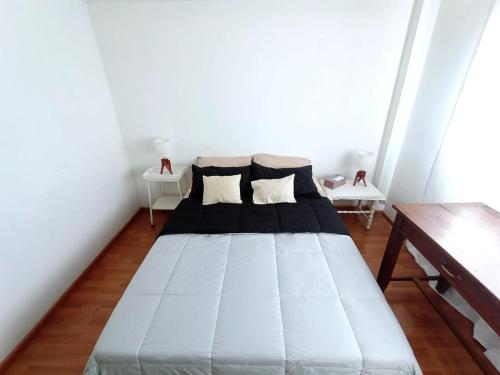 1 cama blanca en una habitación con 2 mesas en Abasto, departamento completo y práctico en Buenos Aires