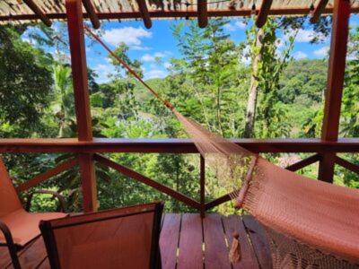 a porch with a hammock and a chair and trees at Boca Tapada Lodge in Boca Tapada
