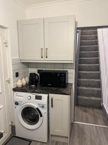 a kitchen with a washing machine and a staircase at 3 Bedroom fully equipped house with garden in Manchester