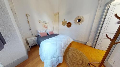 um quarto com uma cama com lençóis brancos e almofadas cor-de-rosa em Le Prieuré em Dole
