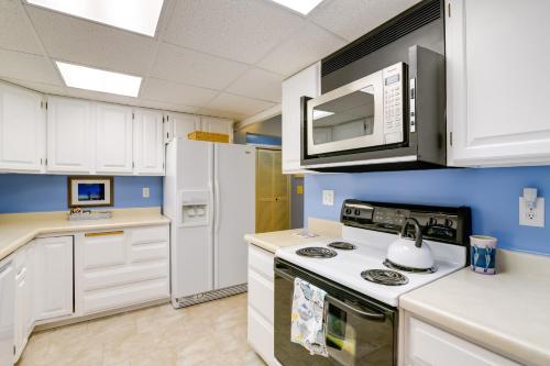 a kitchen with white cabinets and a stove and microwave at Anchorage Vacation Rental Near Coastal Trail! in Anchorage
