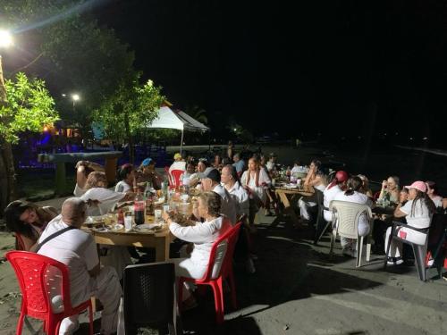 un grupo de personas sentadas en las mesas de noche en HOSTAL BELLEZA TROPICAL, en Moñitos