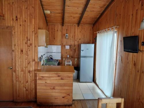 a kitchen with wooden walls and a refrigerator at Refugio Humboldt in Punta de Choros