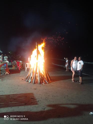 a fire pit on the beach with people standing around it at HOSTAL BELLEZA TROPICAL in Moñitos