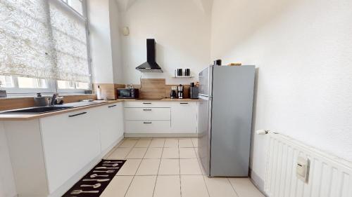 eine Küche mit weißen Schränken und einem Kühlschrank in der Unterkunft Le Prieuré in Dole