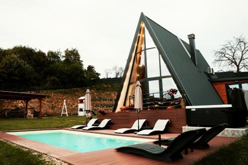 a swimming pool with lounge chairs next to a house at Forrest Relax & Spa in Rakovac