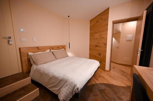 1 dormitorio con 1 cama y pared de madera en Lucalì Mountain Room, en Ponte di Legno