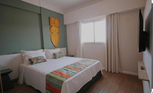 a bedroom with a bed and a large window at Hot Beach Suites in Olímpia