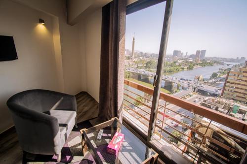 Nile Guardian Hotel في القاهرة: غرفة بها كرسي ونافذة كبيرة