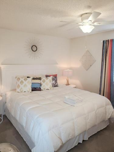 a bedroom with a large white bed with a ceiling fan at Jacob's Well in Redding
