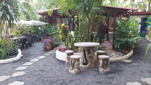 un jardín con mesa y taburetes frente a un edificio en Hotel y Restaurante Mama Ines, en Santa Catalina