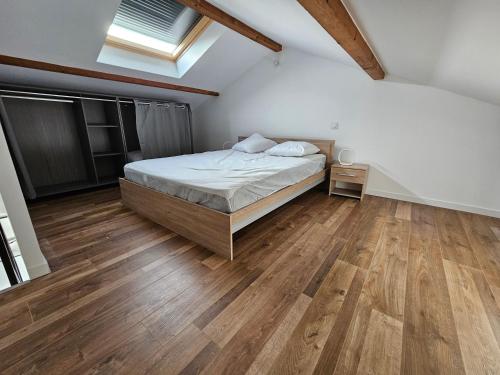 a bedroom with a bed and a wooden floor at appartement guy in Priay