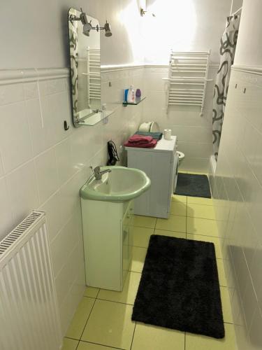 La salle de bains blanche est pourvue d'un lavabo et d'un miroir. dans l'établissement Apartament REJA CENTRUM, à Kętrzyn