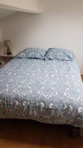 a bed with a silver comforter and two pillows at Appartement T2 face au golf in Buzet-sur-Tarn