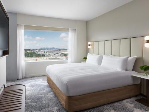 a bedroom with a large bed and a large window at PARKROYAL Melbourne Airport in Melbourne